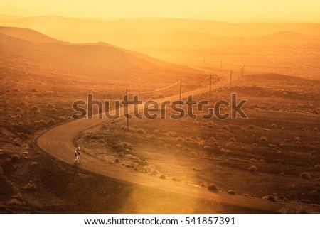 A road cyclist is riding his bike on a lonely road through the desert of Fuerteventura, Spain.
