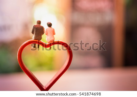 Miniature of a women and a man in love sitting on heart sign bench with bokeh light copyspace, couple in love and pre-wedding background concept Royalty-Free Stock Photo #541874698