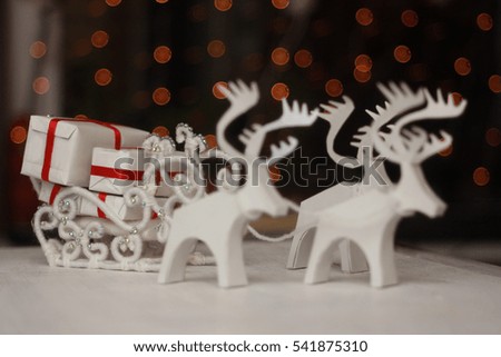 White Christmas sleigh drawn by white reindeer pulling a gifts on a dark background. handmade