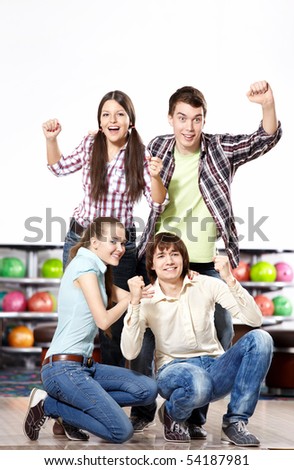 Young attractive people rejoice at game in bowling