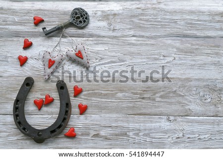 Horseshoes with red  hearts , key on wooden background 