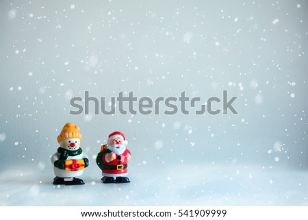 Santa Claus and a snowman holding a gift box in the snow.