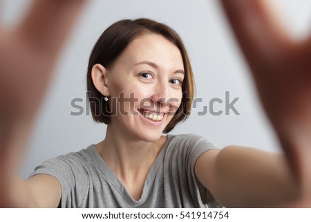 Taking picture. Smiling cheerful girl with freckles doing selfie. Stretching the hands to the camera