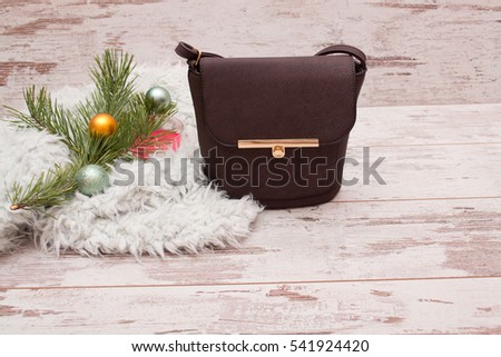 Small brown female handbag on a wooden background, fir branch with decorations. Fashion concept with space for text