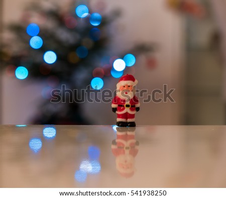 Fun Father Christmas figurines on white surface with Christmas lights in the background.