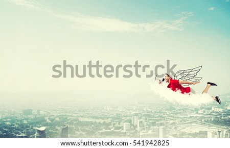 Young cheerful man with megaphone flying high above city