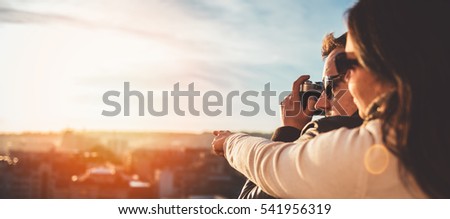 Couple taking pictures of the sunset on the rooftop