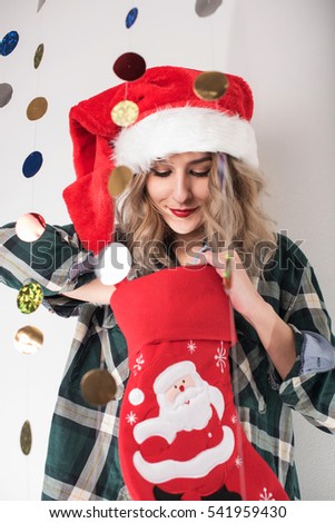 young woman with Christmas hat looking inside Christmas sock 