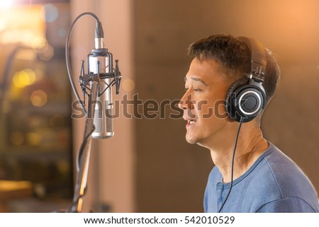 
Male  singer wearing headphone during voice recording in front of high fidelity microphone at recording studio,blurred background
Man singing in front of condenser microphone.