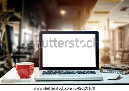 Front view of cup and laptop on table in Office in fitness gym in morning light
