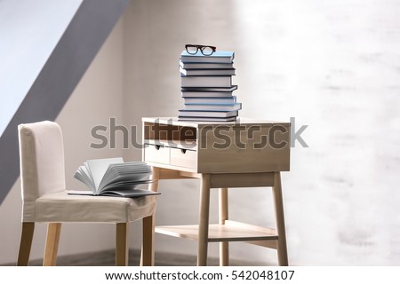 Small wooden table with books and chair in empty room
