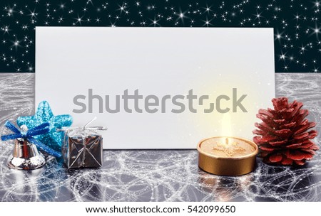 Christmas card with envelope for greetings,Festive Christmas decoration,Red Pine cone,Gold Candle,Silver Jingle bell .Stars in the background.