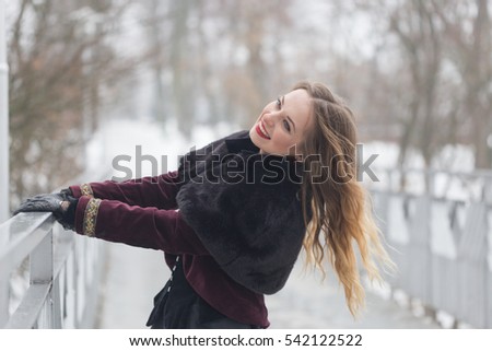 beautiful girl standing on the pedestrian bridge in winter.