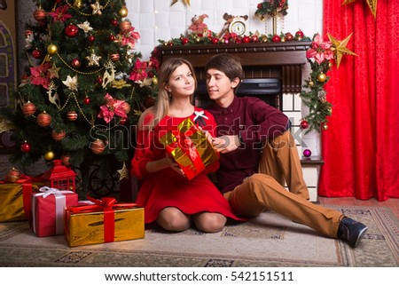 Beautiful young loving couple and around the Christmas tree in the new year
