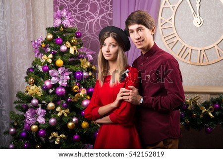 Beautiful young loving couple and around the Christmas tree in the new year
