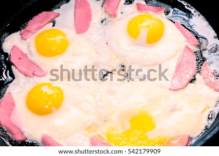 tasty fried eggs with fresh sausages in a pan
