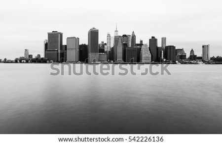 Manhattan skyline in cloudy day, New York skyscrapers reflected in water, black and white photo, USA