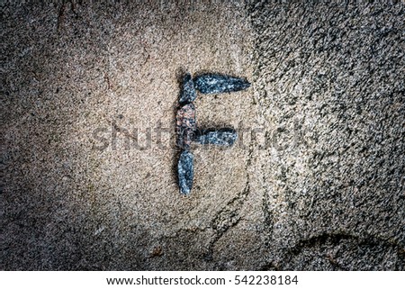 Latin letter "F" paved stones on the rock. View from above, image vignetting and highlighting the center