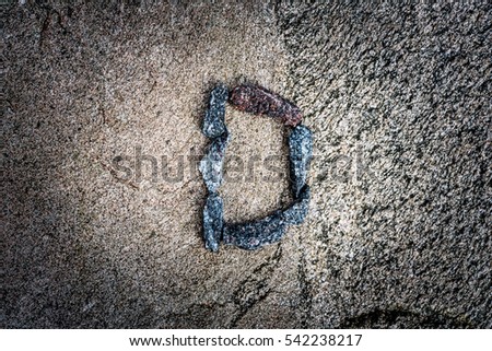 Latin letter "D" paved stones on the rock. View from above, image vignetting and highlighting the center