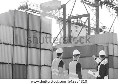 Rear view of workers inspecting cargo containers in shipping yard