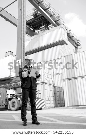 Full-length of male supervisor writing on clipboard in shipping yard