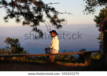 Bench in the autumn park,beautiful young woman with long hair sitting on the bench watching mountains.
