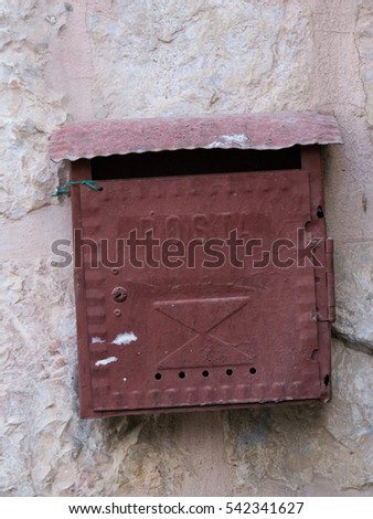 old dark red mail box on a stone wall