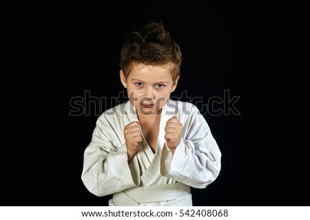 Young boy in kimono shows the martial arts on a black background