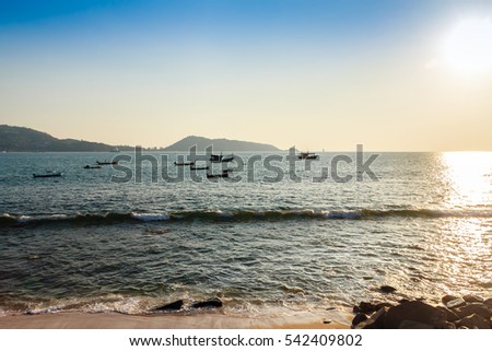 Beautiful scenery view of Patong beach in blue sky daylight and mountain background with local fisherman long tail boats and tourist luxury cruises. Patong is the popular beach in Phuket, Thailand.