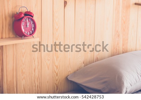 Red alarm clock on wood shelf in bedroom at home