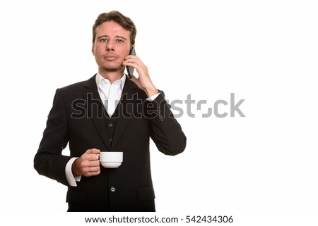 Handsome Caucasian businessman talking on mobile phone while holding coffee cup isolated against white background