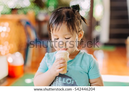 Cute happy baby girl are eating ice cream in summer with put out tongue. Picture for concept of sweet ,fat ,obesity and diabetes in children.