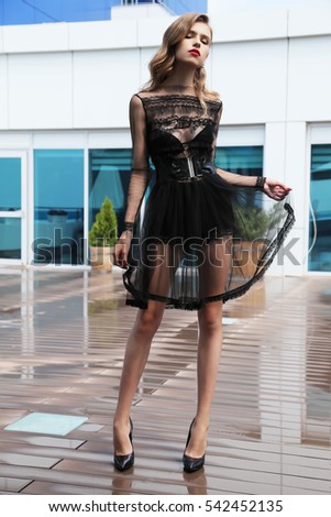 fashion photo of beautiful young woman with long hair in luxurious dress posing in outdoor cafe