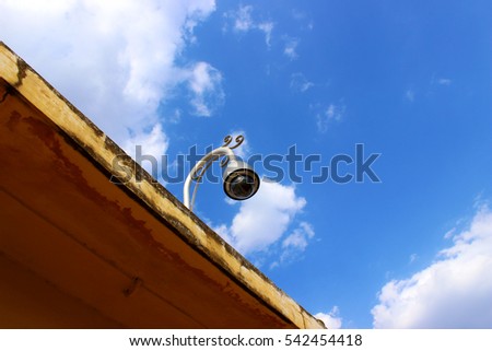 Security camera fixed on the roof of a building with blue sky and clouds in the background 