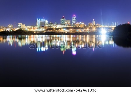 A skyline view of Kansas City over the Missouri River with reflections on the water.
