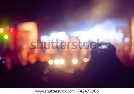 Blur people taking smart phone in night outdoor concert with colorful bokeh abstract background. Copy space of activity and lifestyle concept. Vintage tone filter effect color style.