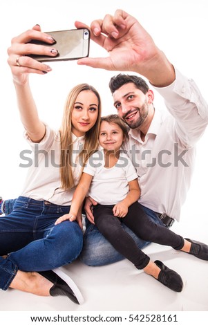 Happy family on white background. Mother, father and daughter take selfie on phone