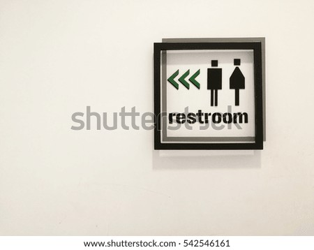 Interior restroom symbol with direction on the white wall