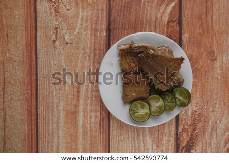Salted fish with lime on wooden background.