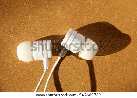 White ear phone close up on golden texture background
