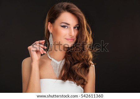 Fashion Brunette Model Portrait. Jewelry and Hairstyle. Elegant lady on black background.