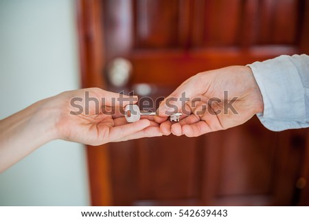 Man's hand gives a key female hand on a background of a wooden door. Deal with the real estate concept.