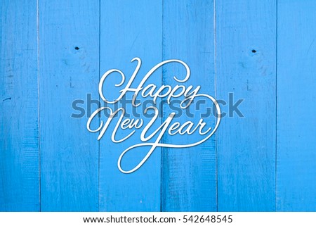 Typography of the happy new year on the blue wooden background Royalty-Free Stock Photo #542648545