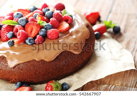 Homemade chocolate cake with berries on brown wooden table