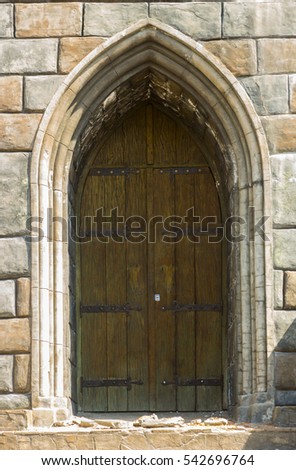 Gothic wooden door with wrought iron elements in the stone wall close up
