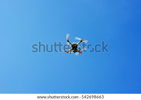 drone quad copter with high resolution digital camera flying hovering in the blue sky