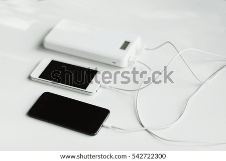 White and black mobile phone with the bank power  (battery bank) on a white background.