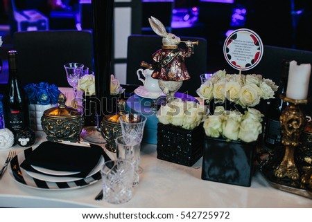 Table decor. Alice in Wonderland. Black boxes with white roses stand on the dinner table