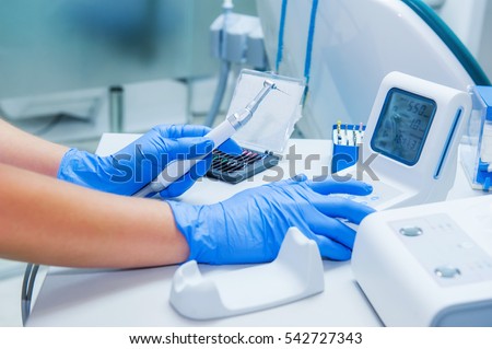 Assistant's hands configures dental equipment in dentist's office. Close up, selective focus. Dentistry Royalty-Free Stock Photo #542727343