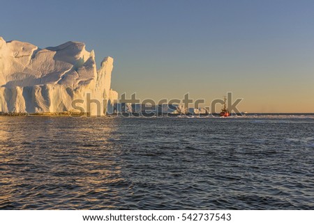 Tourists on the boat take pictures of the icebergs in the Disko Bay, West Greenland. The source of these icebergs is the Jakobshavn glacier due to global warming and catastrophic thawing of ice